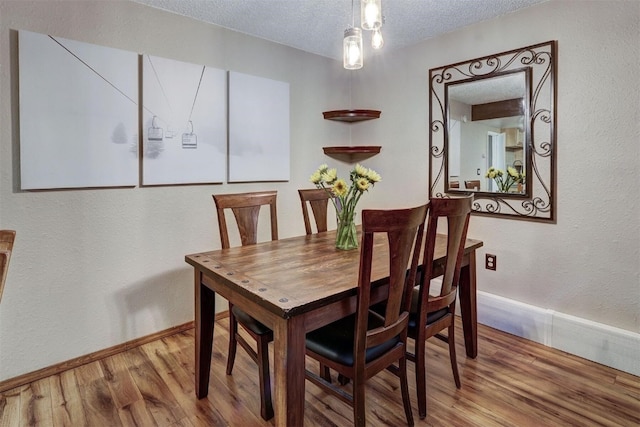 dining room with a textured ceiling and light wood-type flooring