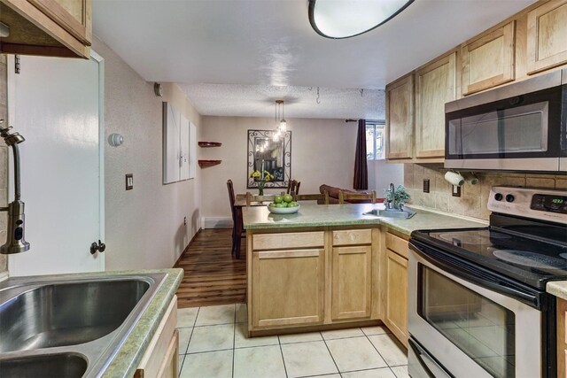 kitchen featuring light brown cabinetry, a textured ceiling, stainless steel appliances, light tile patterned floors, and pendant lighting