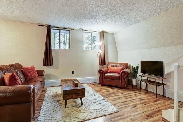 living room featuring a textured ceiling, light hardwood / wood-style flooring, and vaulted ceiling