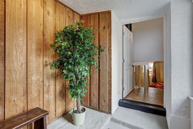 hall featuring a textured ceiling and wood walls