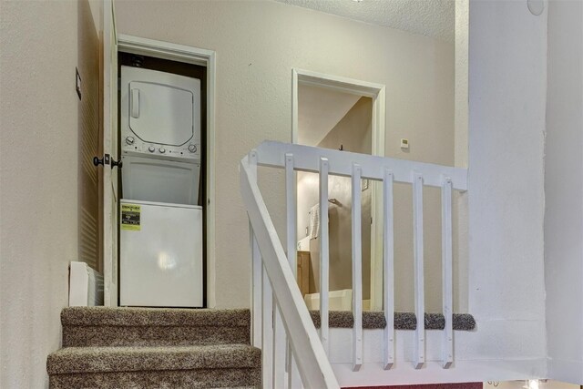 stairs featuring a textured ceiling and stacked washing maching and dryer