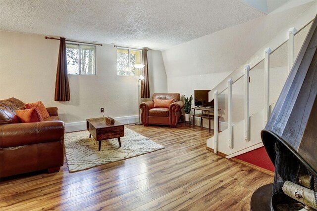 living room with a textured ceiling, light hardwood / wood-style flooring, and vaulted ceiling