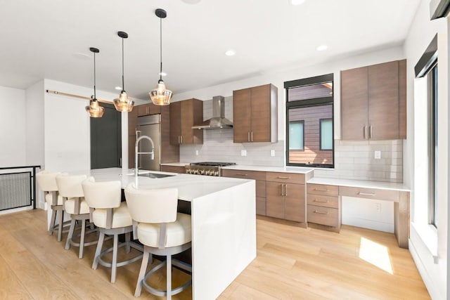 1241 Urban Way, Steamboat Springs, CO 80487 - kitchen featuring wall chimney range hood, light wood-type flooring, backsplash, a breakfast bar area, and recessed lighting