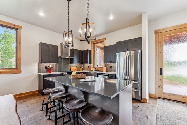 7 Moss Way, Silverthorne, CO 80498 - kitchen with stainless steel appliances, extractor fan, light wood finished floors, a breakfast bar area, and tasteful backsplash