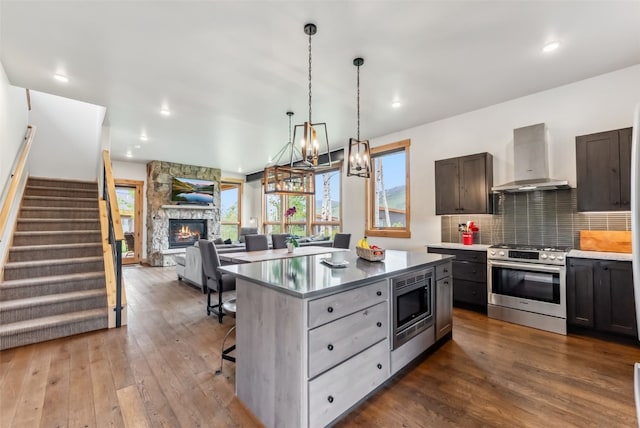 7 Moss Way, Silverthorne, CO 80498 - kitchen featuring stainless steel appliances, wall chimney exhaust hood, a fireplace, decorative backsplash, and dark wood-type flooring
