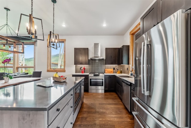 7 Moss Way, Silverthorne, CO 80498 - kitchen with appliances with stainless steel finishes, wall chimney range hood, a chandelier, backsplash, and a kitchen island