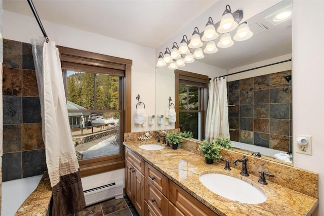 full bathroom featuring a baseboard heating unit, stone finish floor, double vanity, and a sink