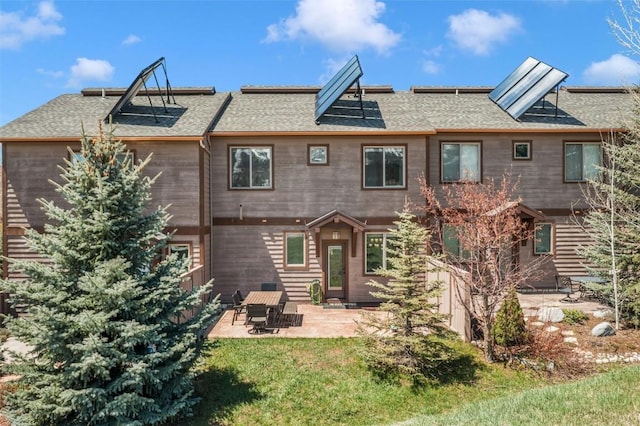 back of house featuring a patio, roof with shingles, and a yard