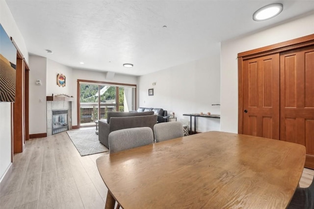 22787 US Highway 6 Unit 302, Keystone, CO 80435 - dining room featuring light wood-type flooring, a tiled fireplace, and baseboards