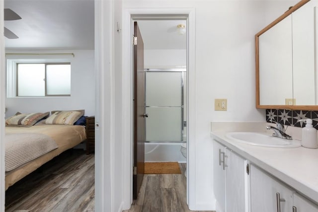 180 Evergreen Rd Unit 105, Dillon, CO 80435 - ensuite bathroom with vanity, wood finished floors, bath / shower combo with glass door, tasteful backsplash, and ceiling fan