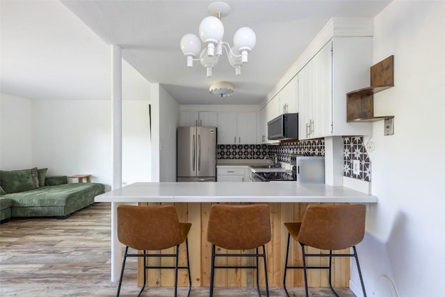 180 Evergreen Rd Unit 105, Dillon, CO 80435 - kitchen featuring freestanding refrigerator, black microwave, a peninsula, tasteful backsplash, and light countertops