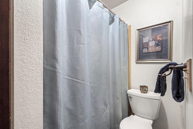 full bathroom featuring toilet, a textured wall, and a shower with shower curtain