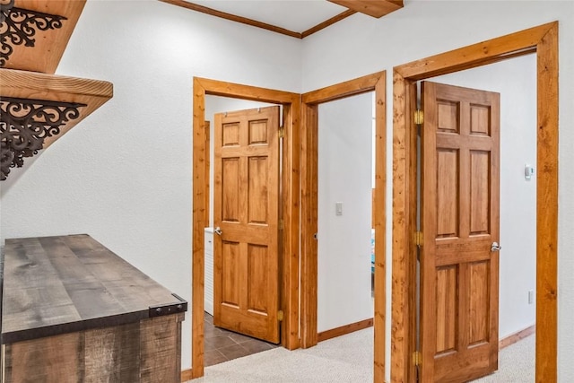 hallway with ornamental molding, baseboards, and tile patterned floors