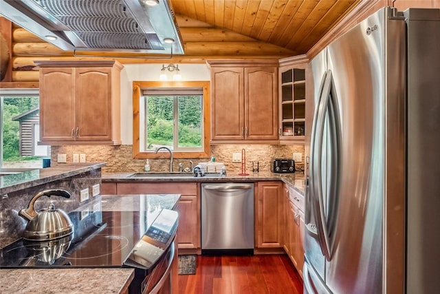 kitchen featuring stainless steel appliances, range hood, dark wood-style flooring, rustic walls, and lofted ceiling