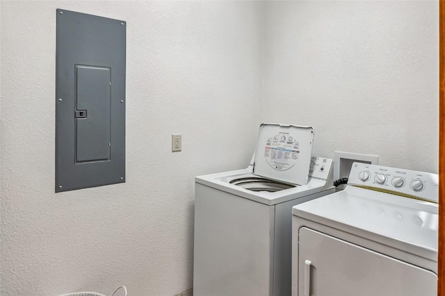 washroom with electric panel, washing machine and clothes dryer, and a textured wall
