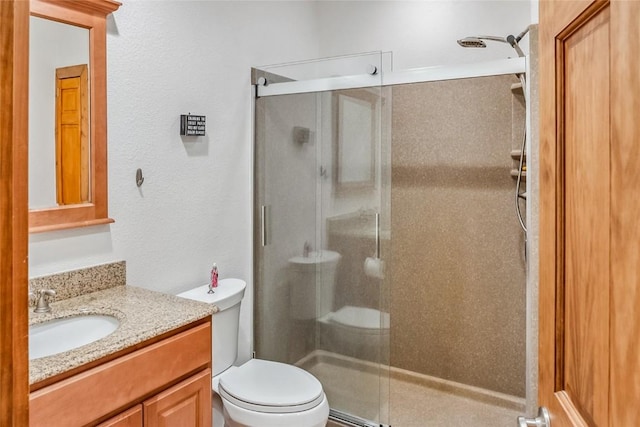 bathroom featuring a shower stall, vanity, toilet, and a textured wall
