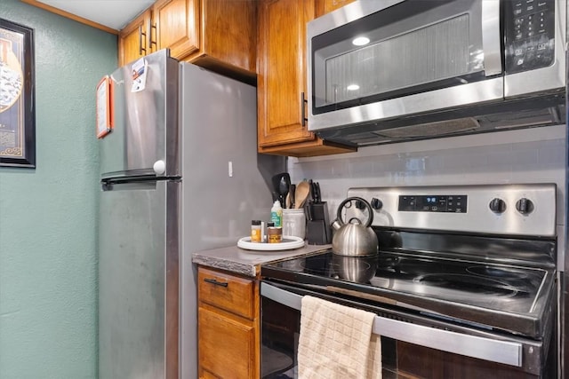 kitchen featuring a textured wall, brown cabinetry, and stainless steel appliances