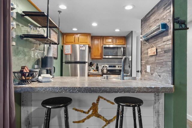 kitchen featuring a peninsula, a kitchen breakfast bar, stainless steel appliances, and a sink