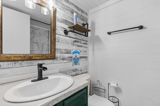 half bathroom featuring wood walls, vanity, and toilet