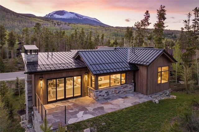 214 Windflower Ln, Frisco, CO 80443 - back of property with a standing seam roof, a forest view, a mountain view, metal roof, and a patio