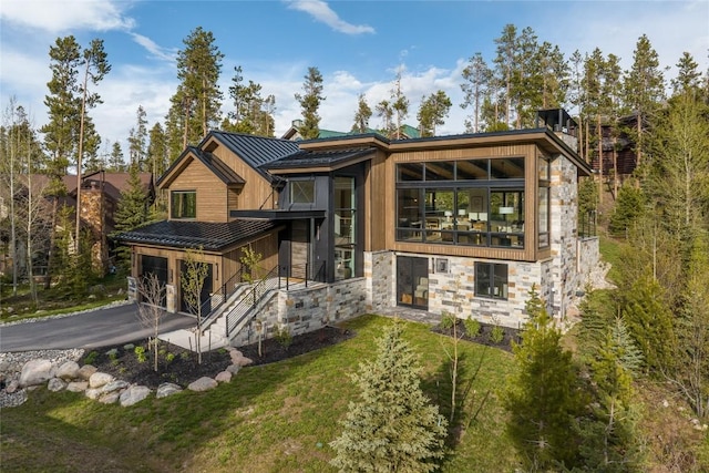 214 Windflower Ln, Frisco, CO 80443 - modern home featuring stone siding, a standing seam roof, a garage, metal roof, and a front lawn