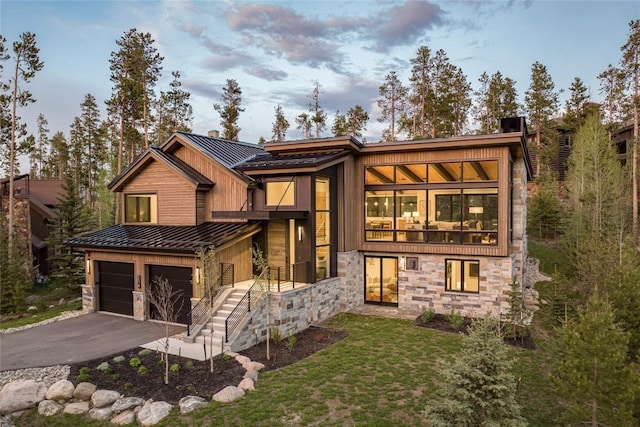 214 Windflower Ln, Frisco, CO 80443 - contemporary house with stone siding, a standing seam roof, a garage, asphalt driveway, and metal roof