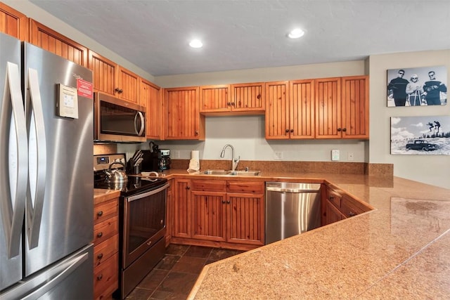 kitchen with recessed lighting, stainless steel appliances, tile countertops, a sink, and stone finish flooring