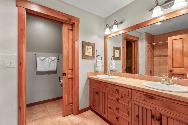 full bath with double vanity, tile patterned flooring, baseboards, and a sink