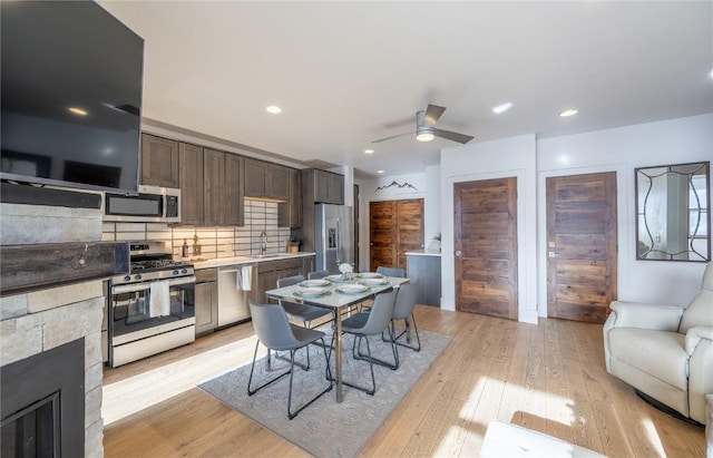 1090 Blue River Pkwy Unit 203, Silverthorne, CO 80498 - kitchen featuring appliances with stainless steel finishes, a sink, light wood finished floors, dark brown cabinetry, and tasteful backsplash