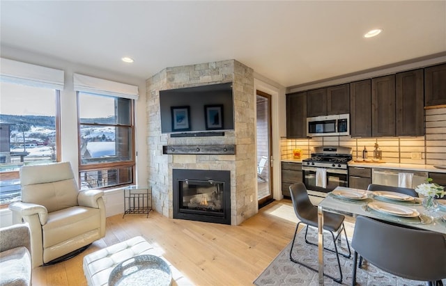 1090 Blue River Pkwy Unit 203, Silverthorne, CO 80498 - kitchen featuring appliances with stainless steel finishes, dark brown cabinets, decorative backsplash, light wood-type flooring, and open floor plan