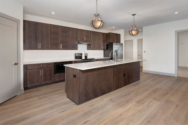 kitchen featuring a sink, light wood-style floors, appliances with stainless steel finishes, light countertops, and under cabinet range hood