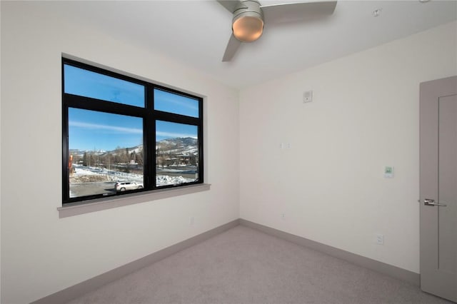 carpeted spare room with ceiling fan and baseboards