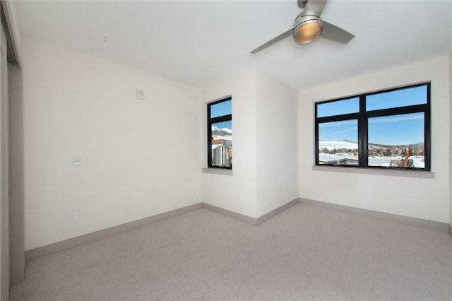 carpeted empty room featuring ceiling fan and baseboards