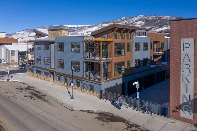 snow covered building featuring a garage and a mountain view
