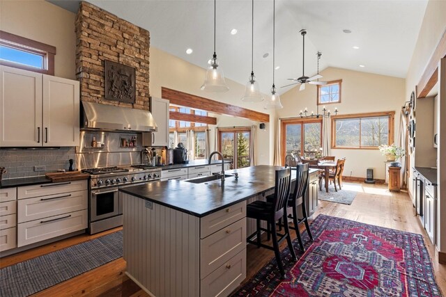 34 Snow Peak Ct, Dillon, CO 80435 - kitchen with range with two ovens, wall chimney range hood, dark countertops, a sink, and ceiling fan