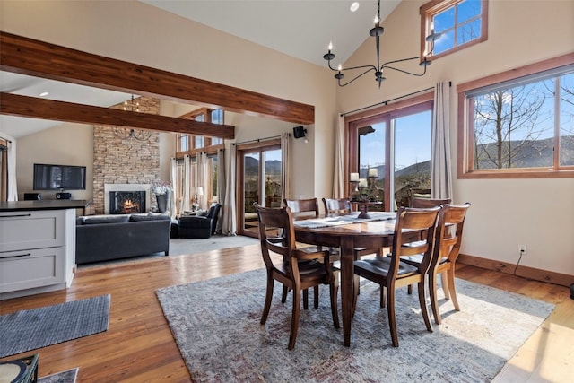 34 Snow Peak Ct, Dillon, CO 80435 - dining area featuring healthy amount of natural light, a chandelier, light wood-type flooring, a stone fireplace, and high vaulted ceiling