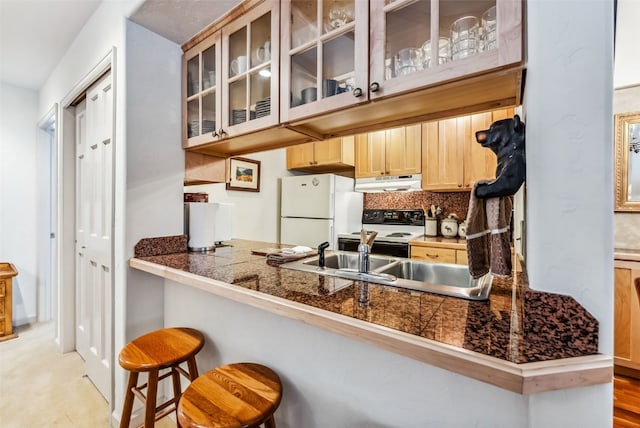 kitchen with sink, kitchen peninsula, white appliances, a kitchen bar, and light brown cabinetry