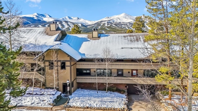 snow covered rear of property with a mountain view and a garage