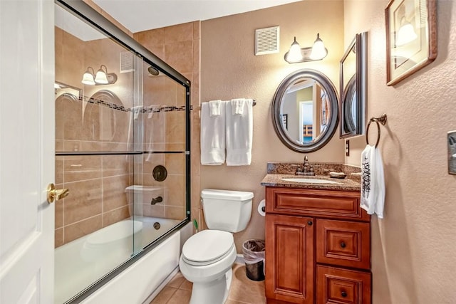bathroom with a textured wall, vanity, toilet, tile patterned floors, and visible vents