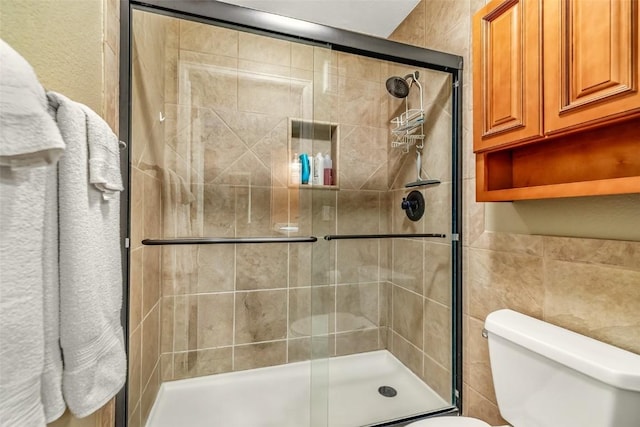 full bathroom featuring tile walls, a stall shower, and toilet