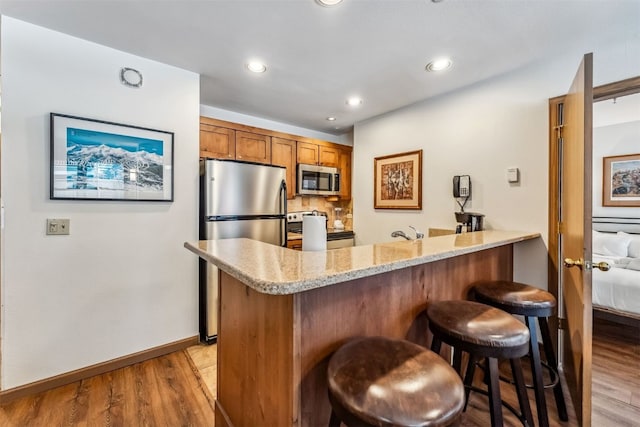 100 S Park Ave Unit E111, 112, Breckenridge, CO 80424 - kitchen with stainless steel appliances, brown cabinets, a peninsula, a breakfast bar, and light wood-type flooring