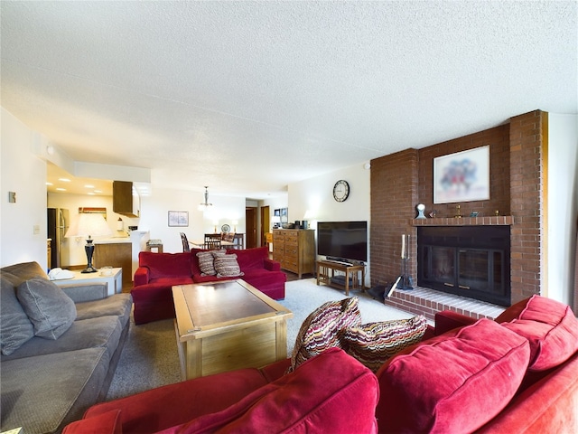 living room featuring carpet, a textured ceiling, and a brick fireplace