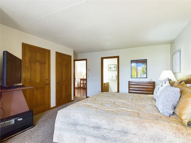 bedroom with carpet, a textured ceiling, and ensuite bath