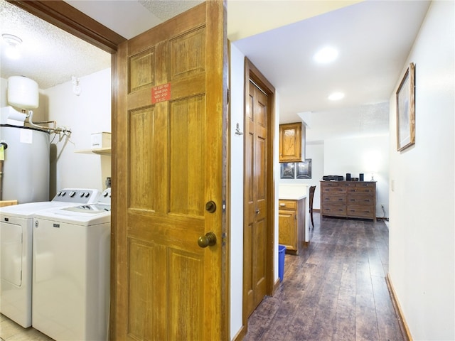 laundry area featuring water heater, dark hardwood / wood-style flooring, a textured ceiling, and washing machine and clothes dryer