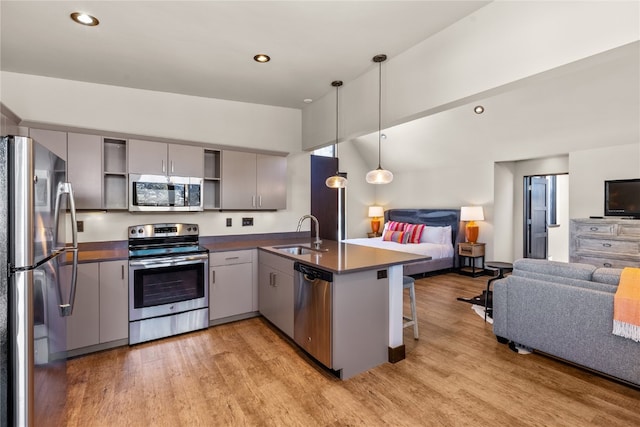 kitchen featuring sink, kitchen peninsula, pendant lighting, gray cabinets, and appliances with stainless steel finishes