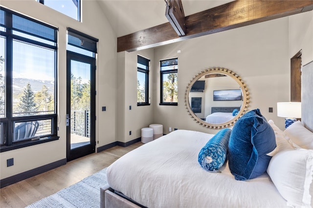 bedroom with a mountain view, access to exterior, light wood-type flooring, and multiple windows