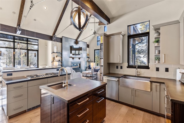 kitchen with beam ceiling, a center island, sink, stainless steel appliances, and dark brown cabinets