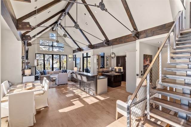 living room featuring beam ceiling, ceiling fan, light hardwood / wood-style flooring, and high vaulted ceiling