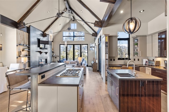 kitchen with a center island with sink, beam ceiling, and a fireplace