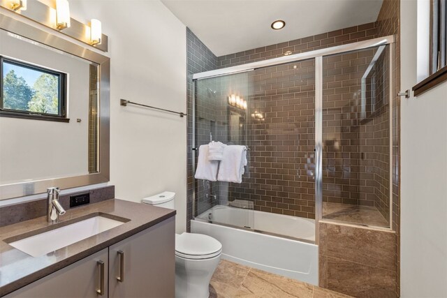 full bathroom featuring vanity, toilet, and shower / bath combination with glass door